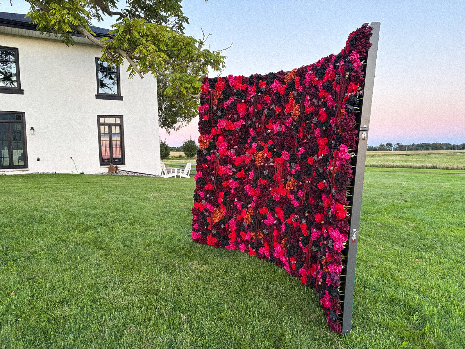 Burgundy flower wall backdrop set up beside a countryside home for a Toronto-area event