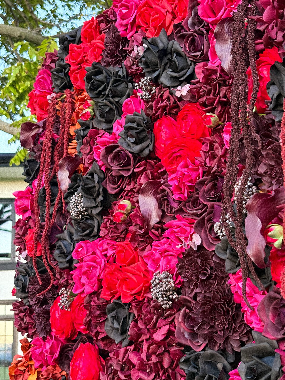 Wide angle view of the Midnight Bloom burgundy Real Touch flower wall outdoors