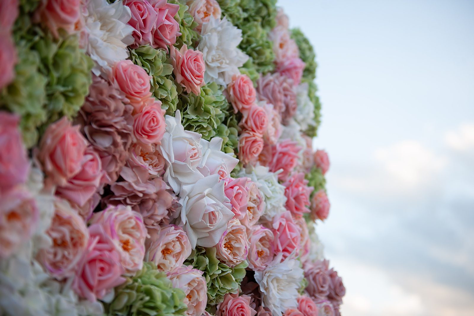 Detail of sage green and blush pink Real Touch roses against a cloudy sky